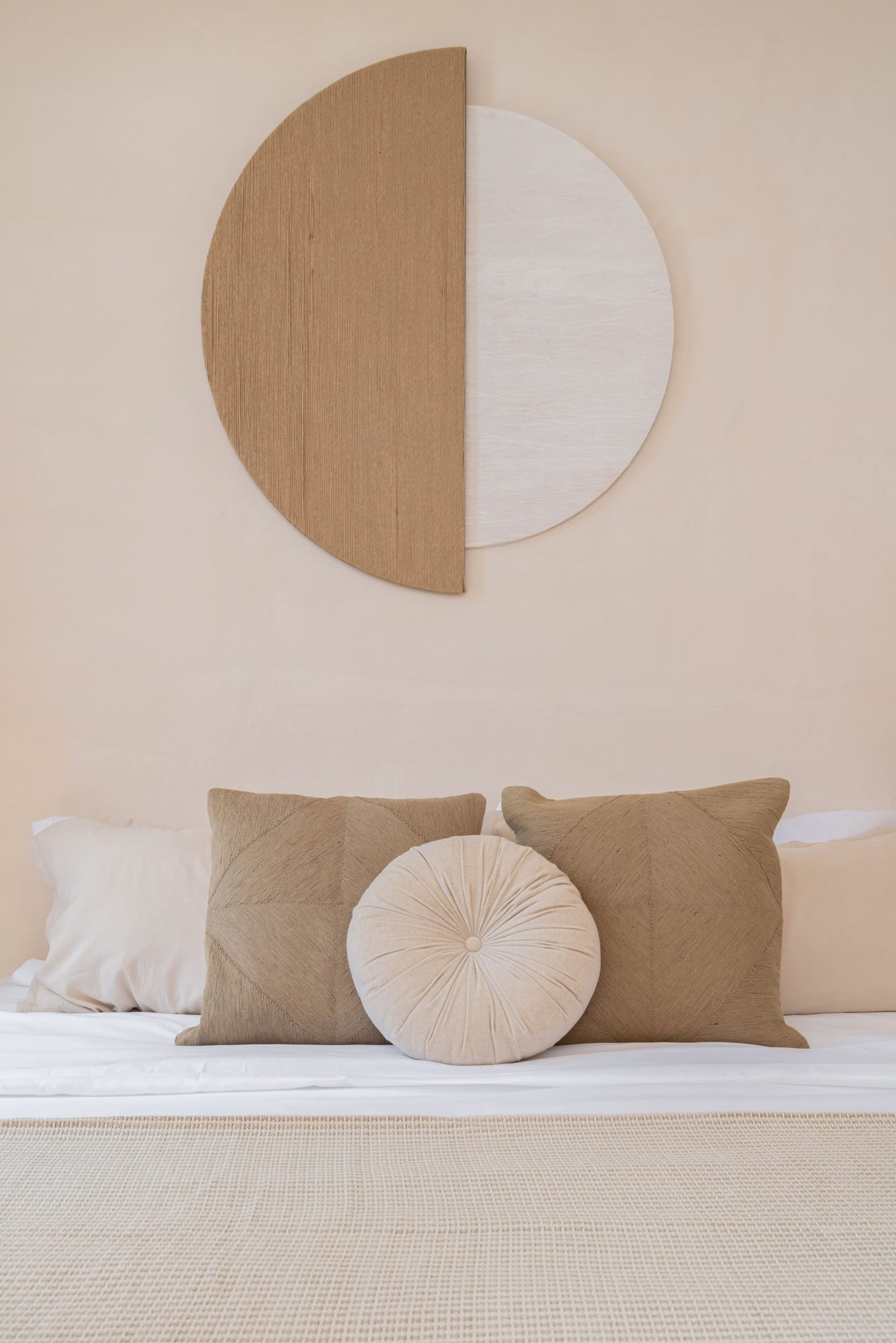 King bed with linen cushions and round wall art