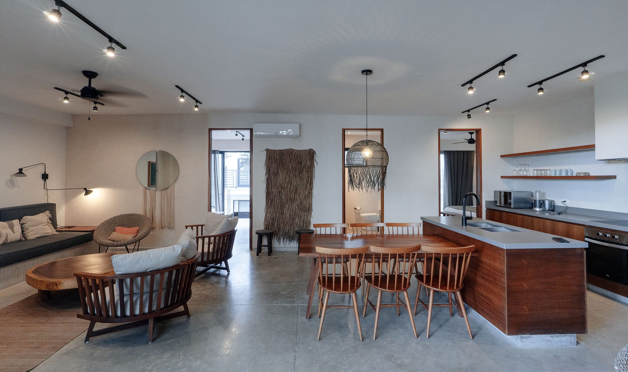 Open-plan living, dining and kitchen area with track lighting and a wooden dining table