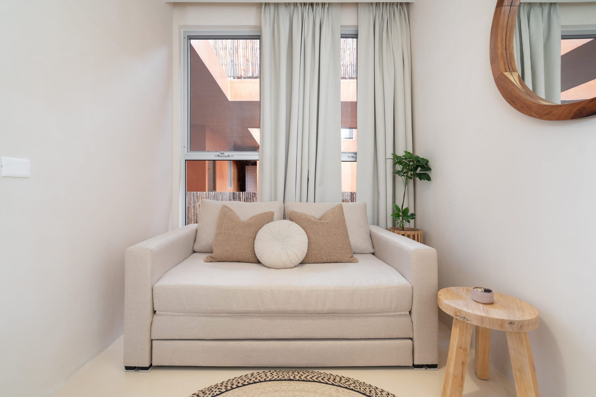 Sofa bed with cushions beside a curtained window