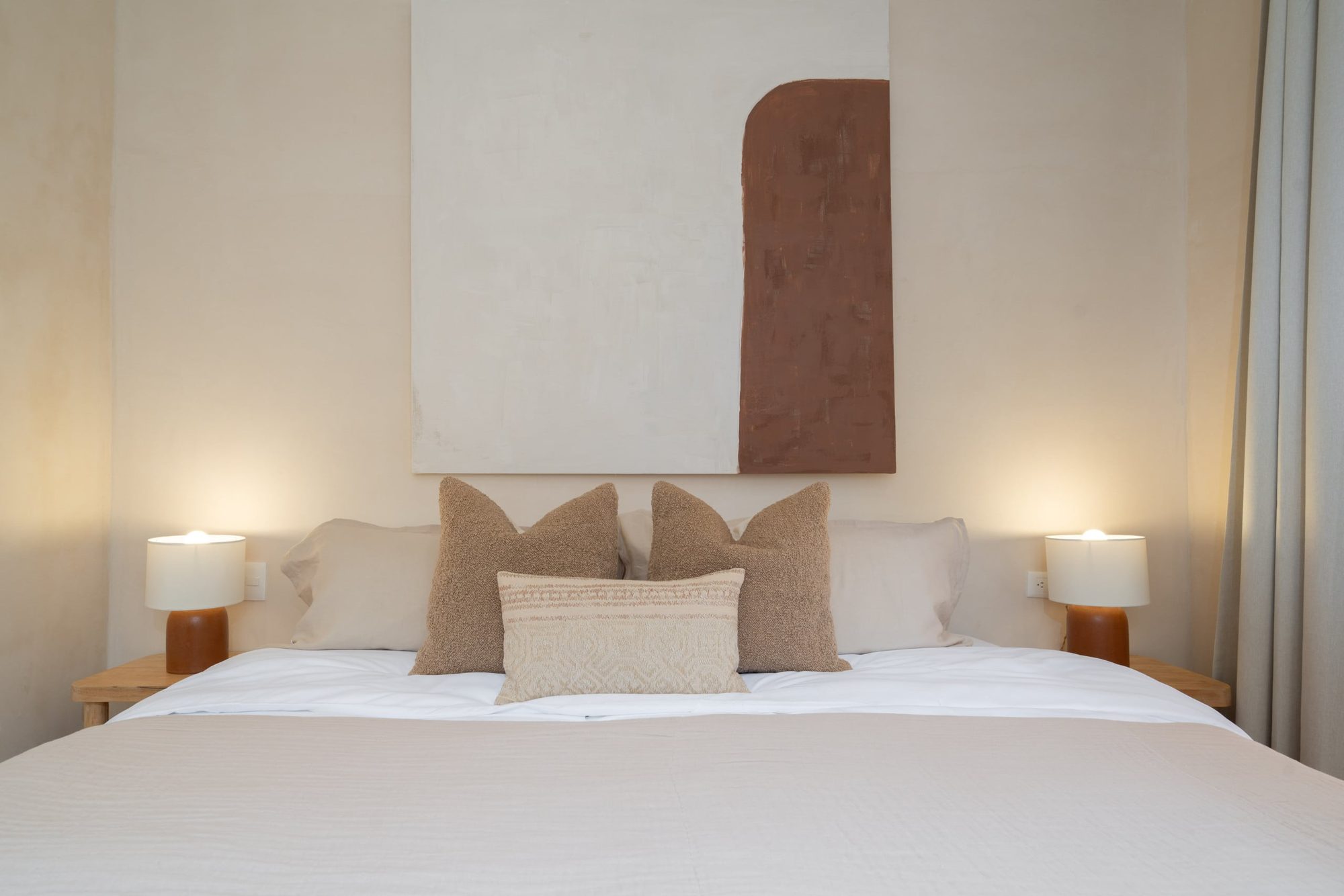 King bed with bedside lamps and terracotta wall art