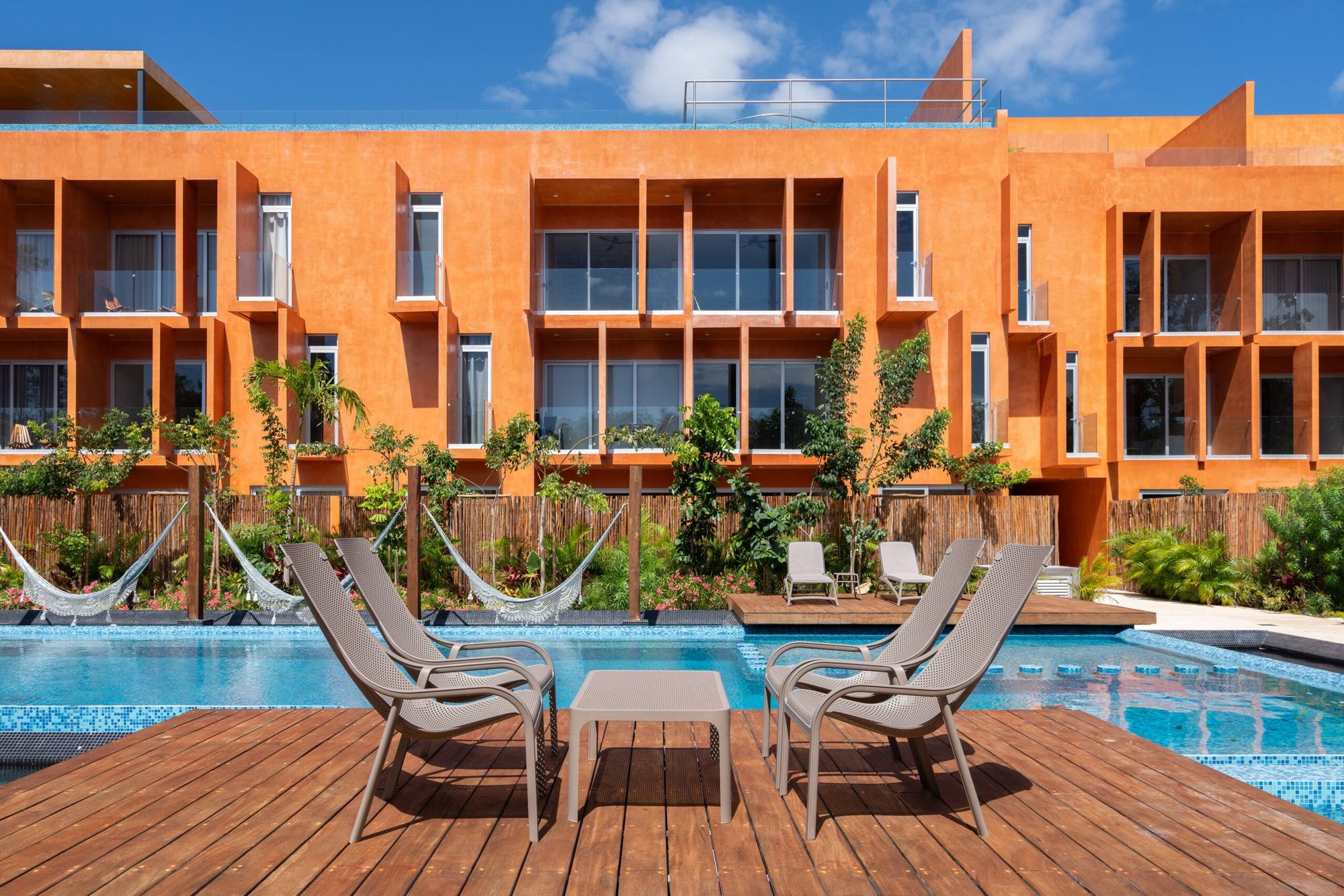 Loungers on a wooden deck by the pool with the buildings behind