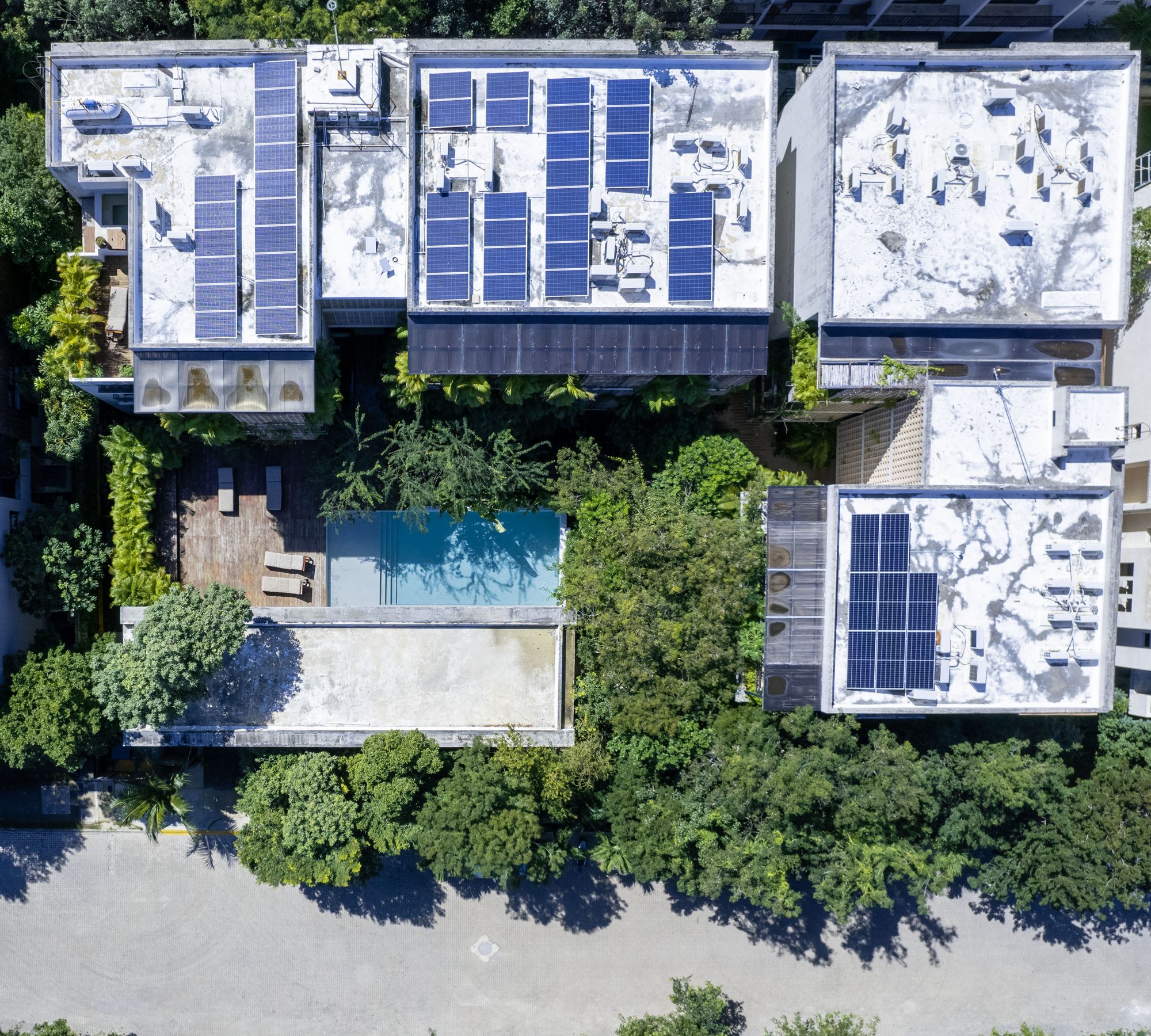 Aerial view of the buildings and pool among the jungle canopy