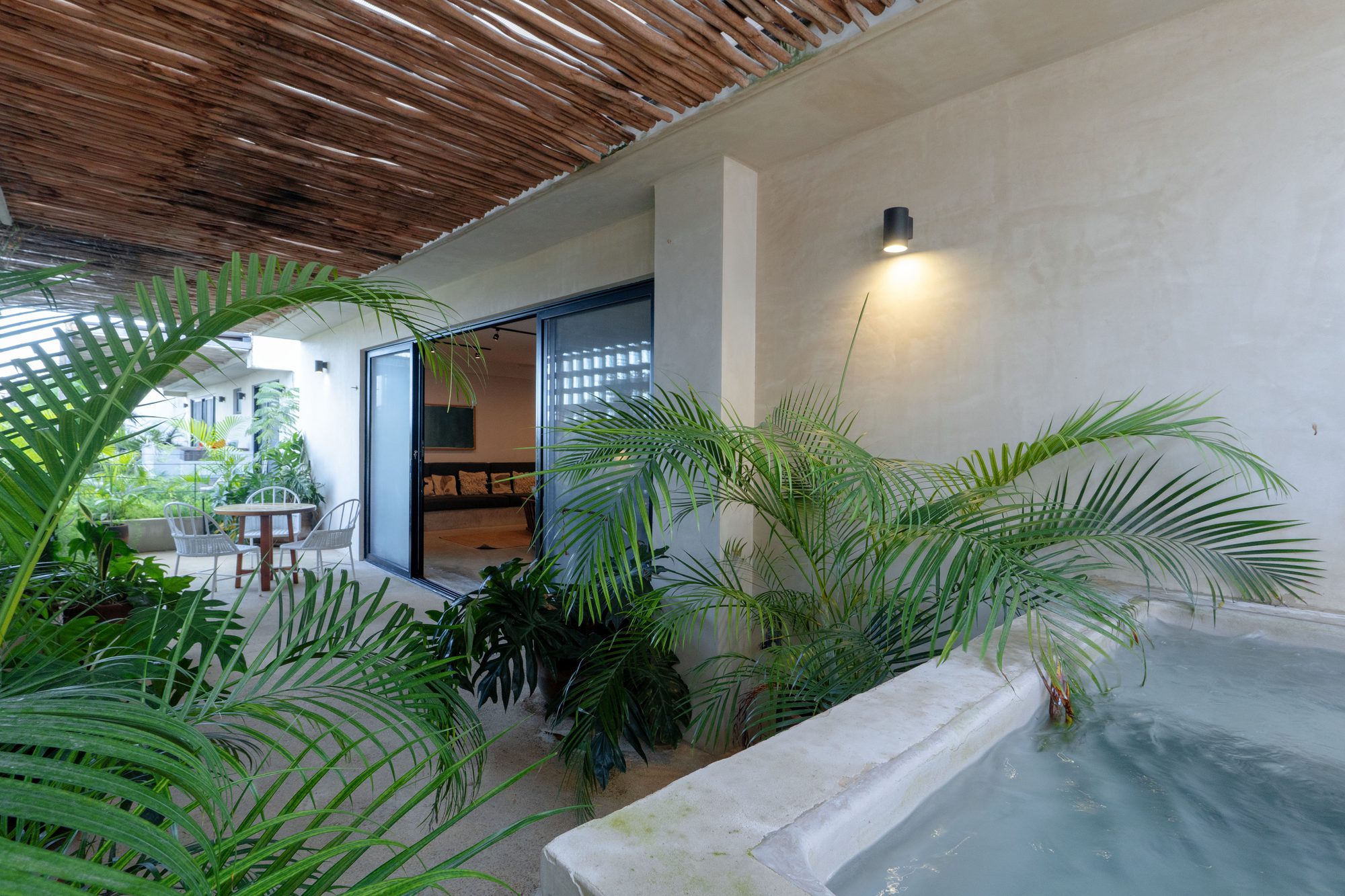Pool on a terrace framed by palms and a woven shade ceiling