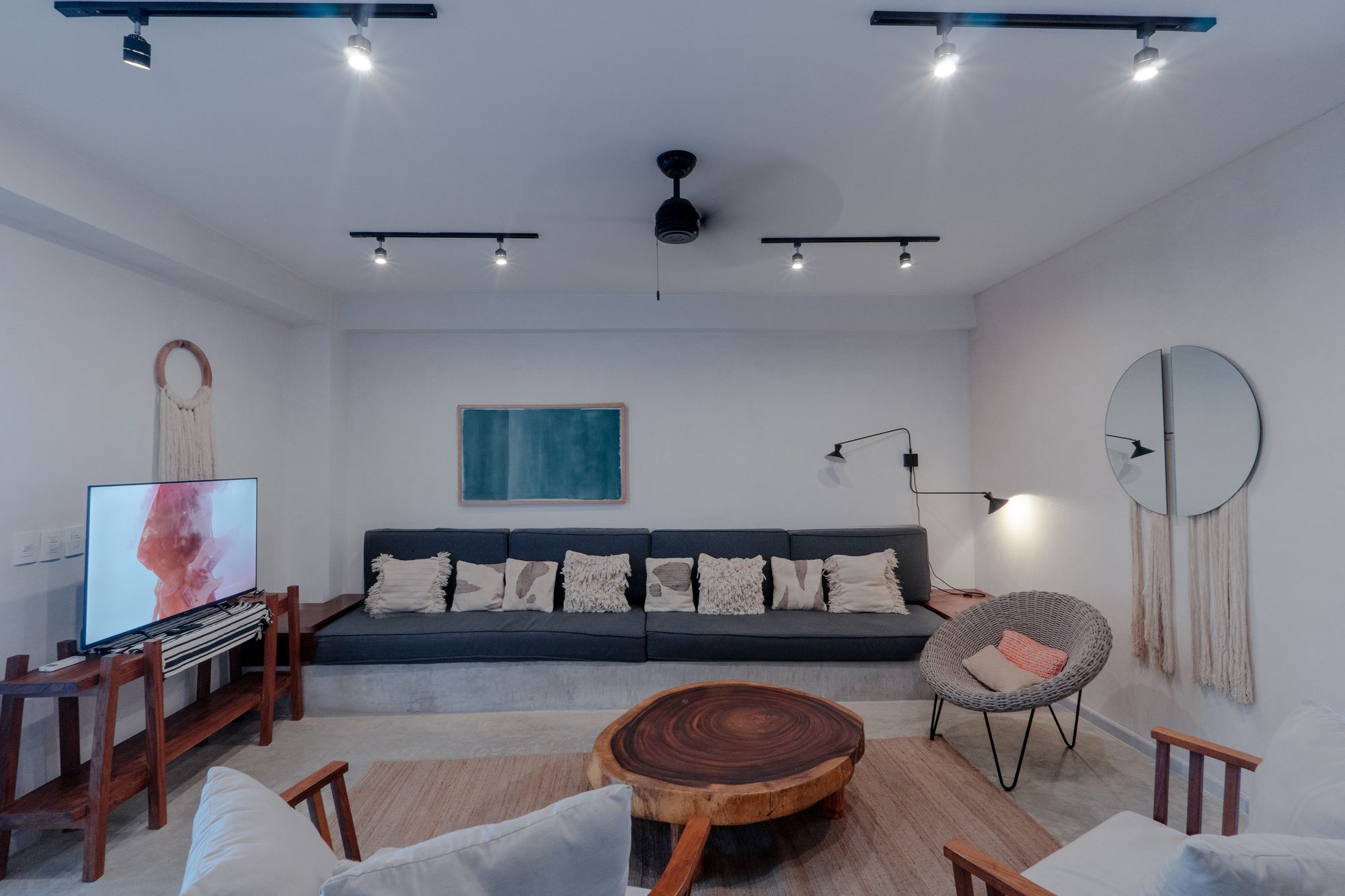 Living room with built-in sofa, TV, round wooden coffee table and a woven wall hanging