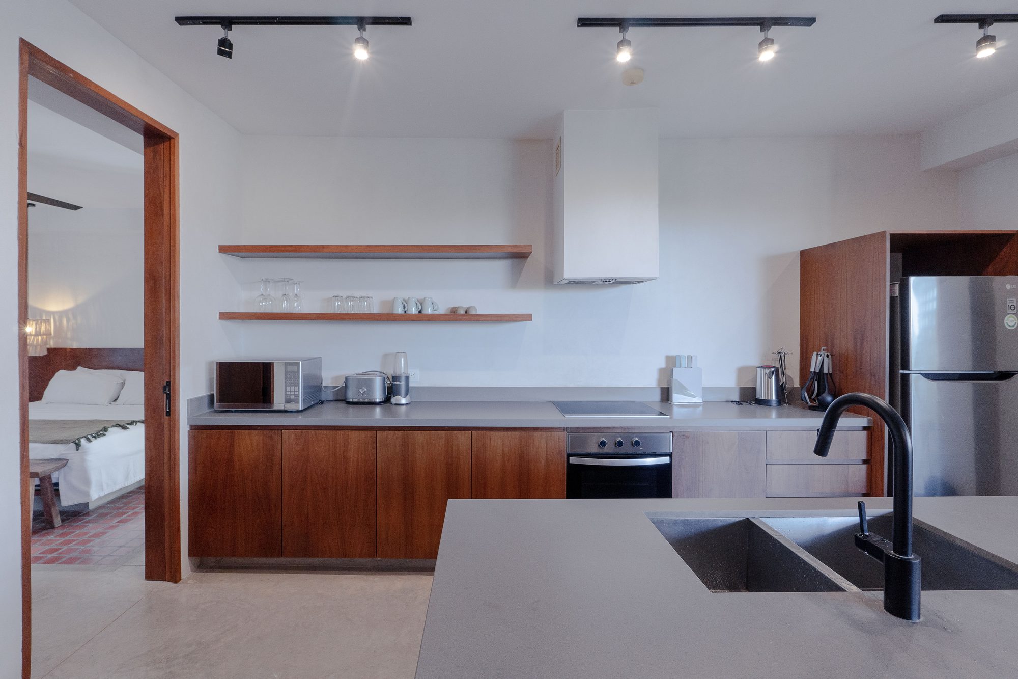 Full kitchen with wood cabinets, stainless steel fridge, cooktop, microwave and open shelving