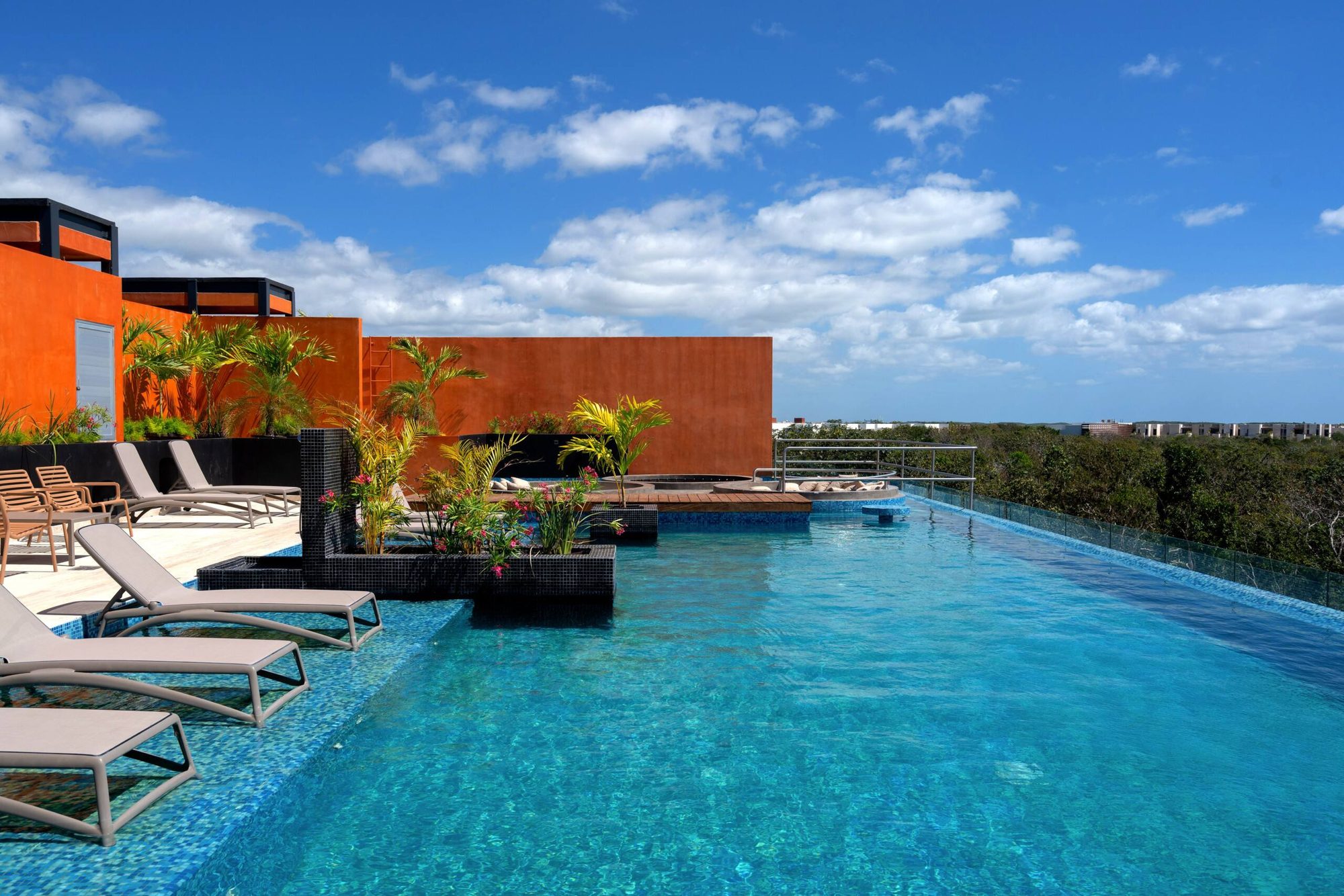Rooftop pool with loungers set in the water and jungle views