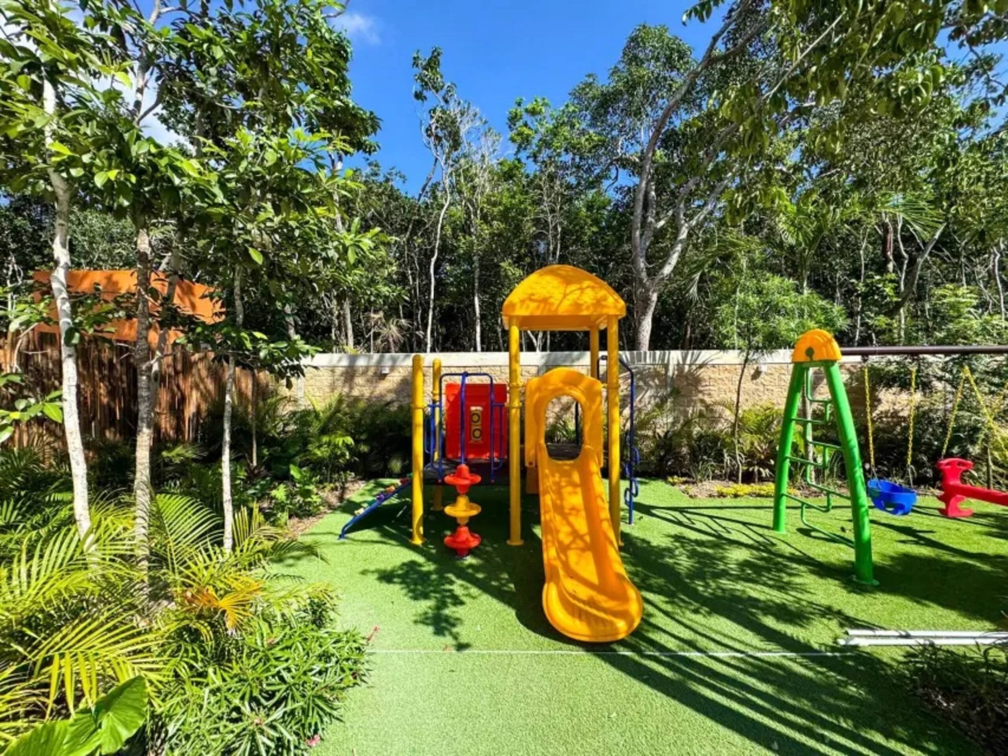 Children's playground on artificial grass among trees