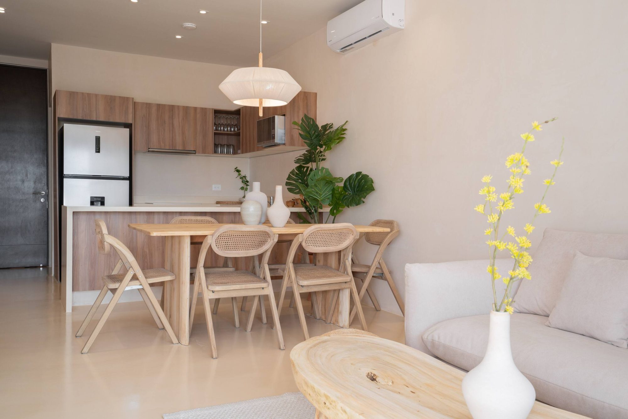 Dining table for six with rattan chairs and the kitchen behind