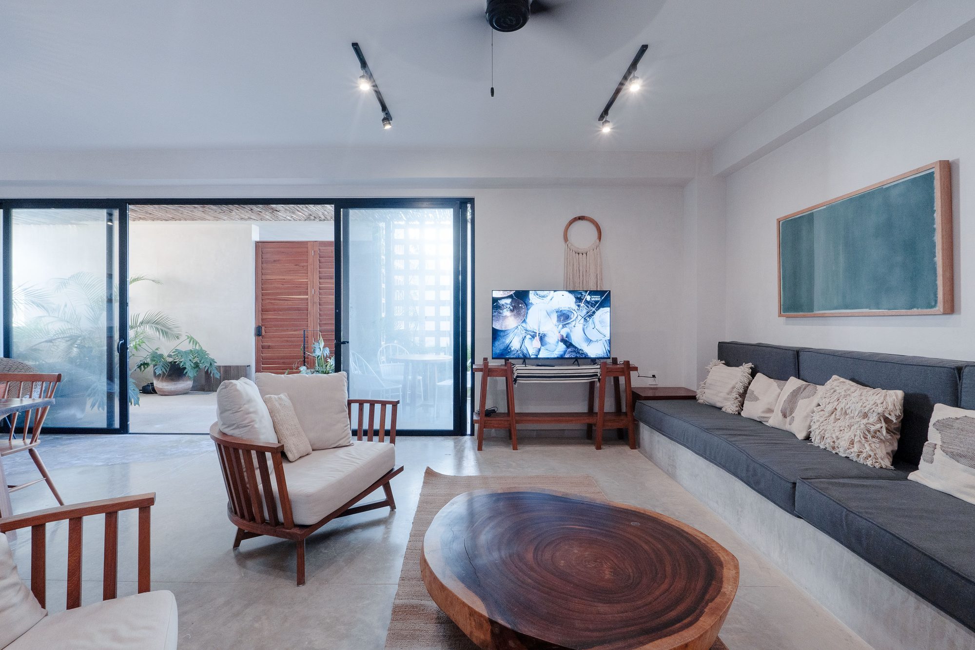 Living room with a long built-in sofa, wood slab coffee table, armchair and TV beside glass doors