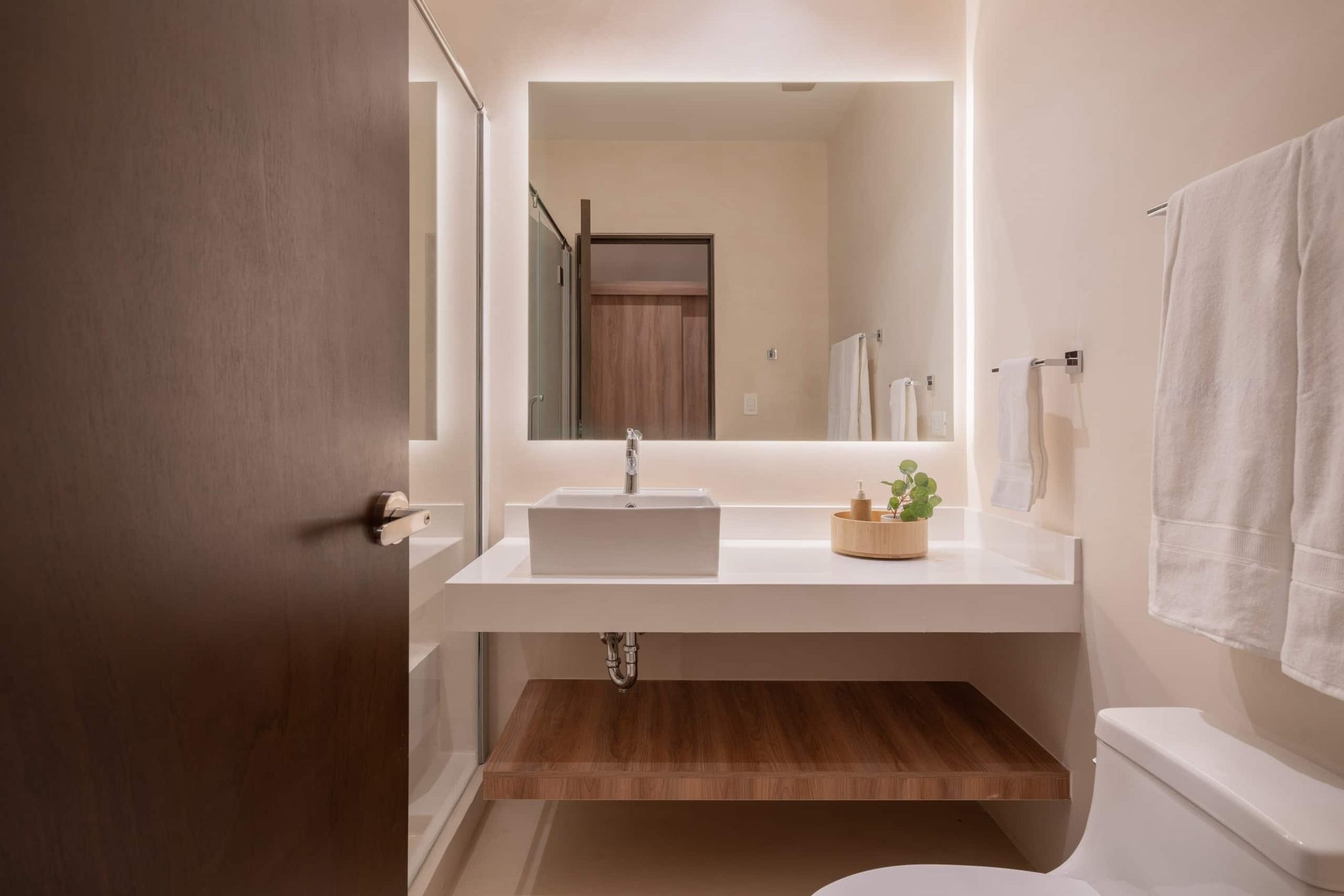 Second bathroom with a backlit mirror and vessel sink