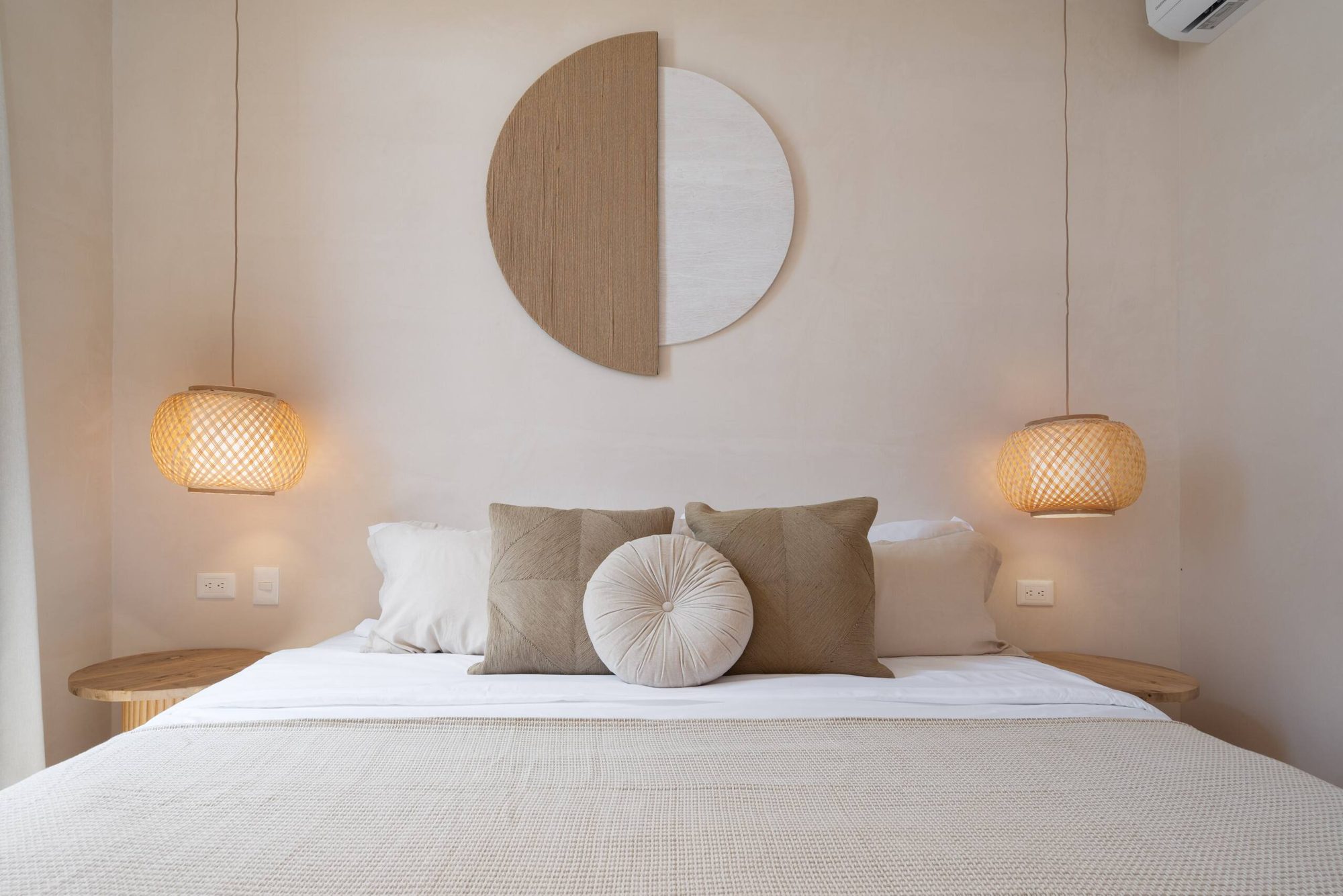 King bed with woven pendant lamps and a round wall art piece