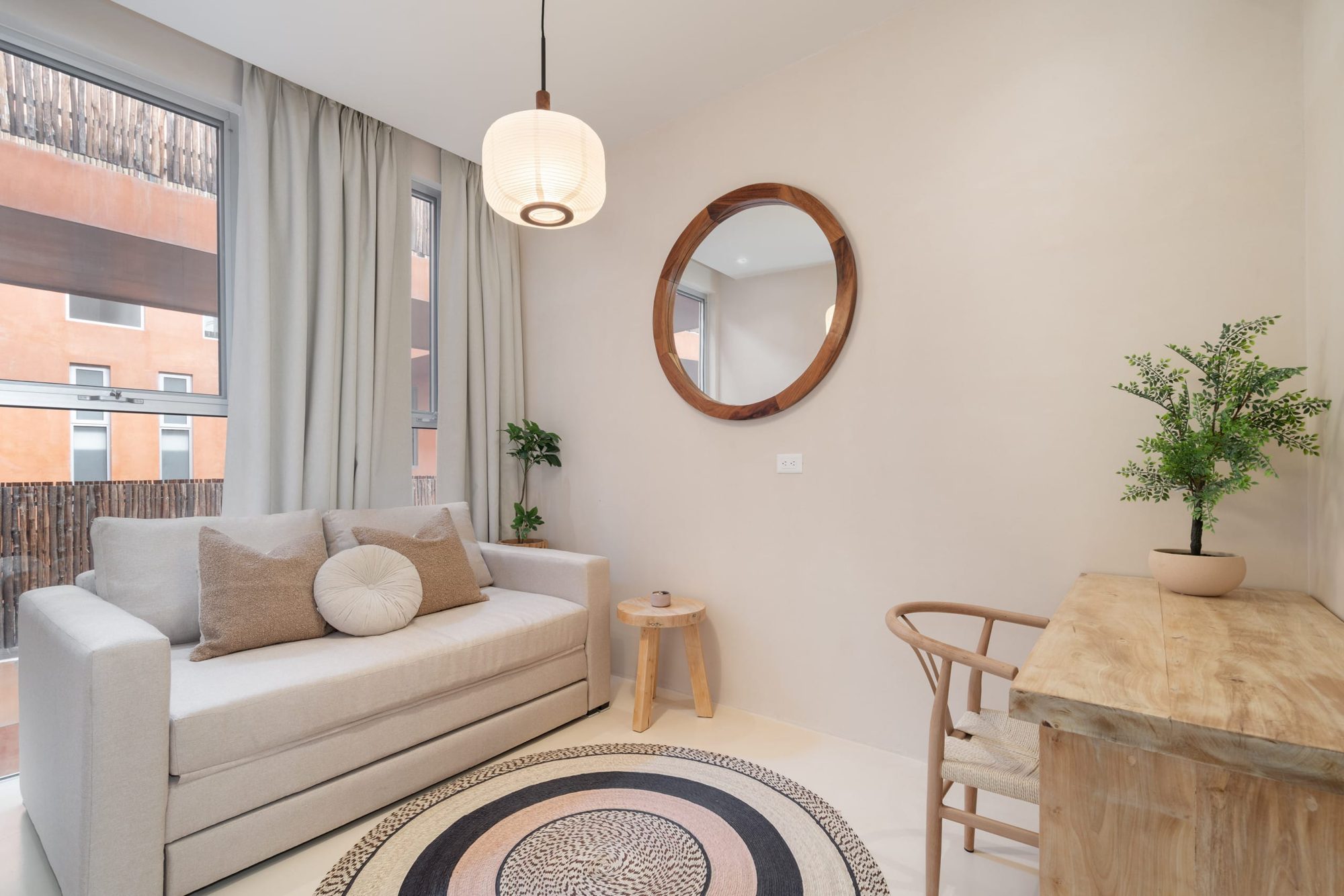 Third bedroom with a sofa bed, round mirror and wood desk