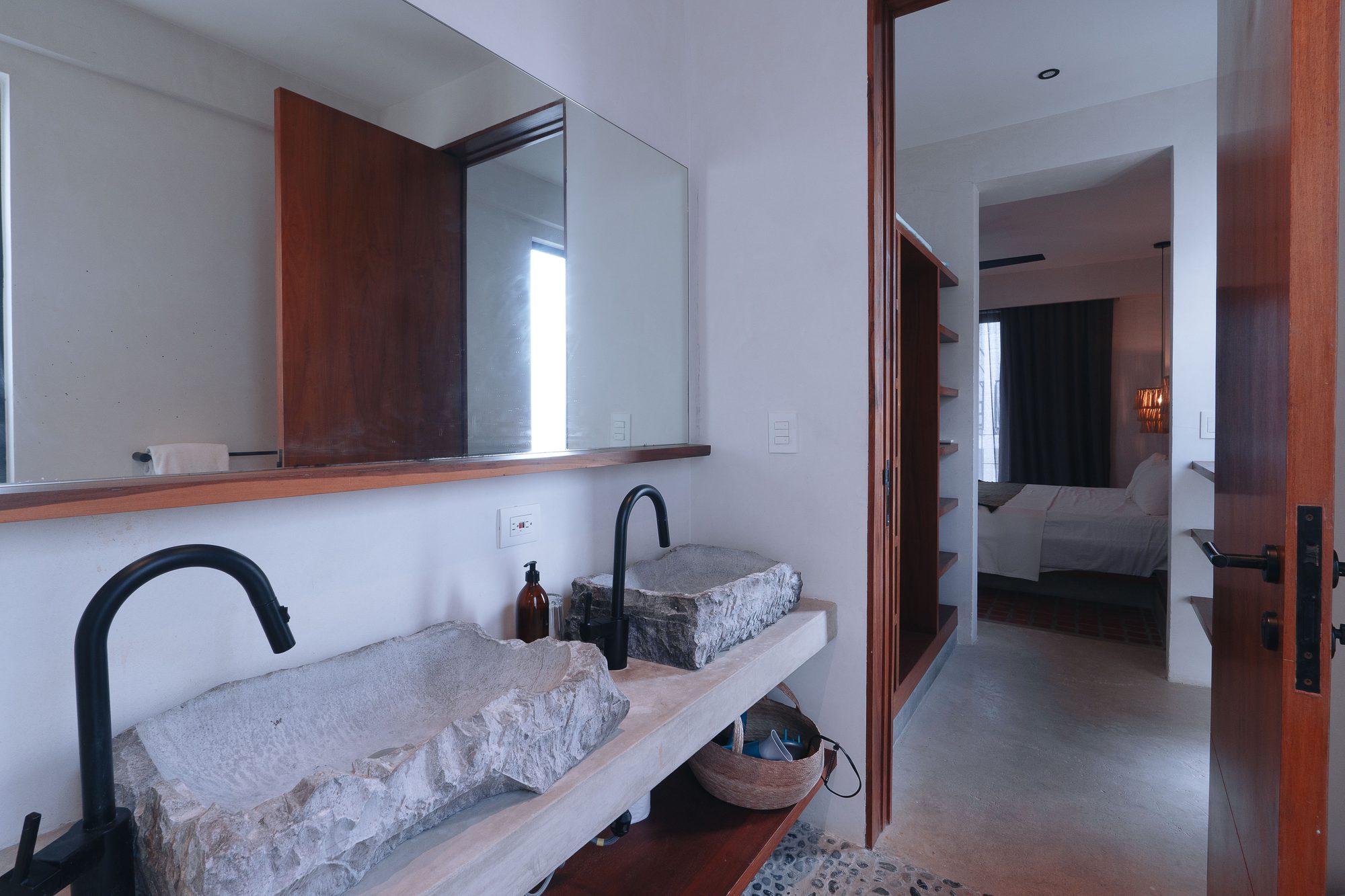 Bathroom with twin stone basins, black faucets and a large mirror