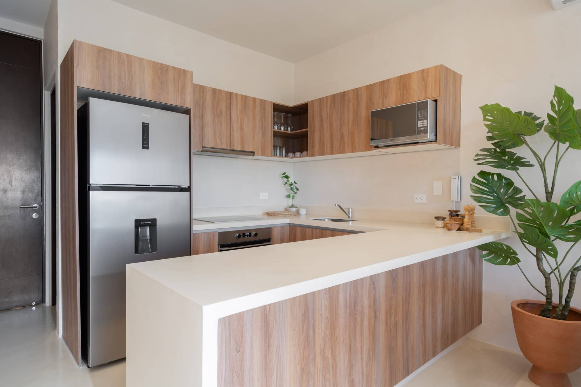 U-shaped kitchen with a stainless steel fridge and plants